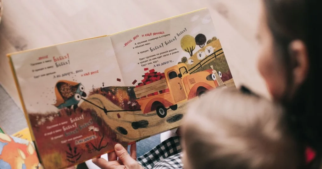 Parent reading a bedtime story to an 18-month-old before sleep.