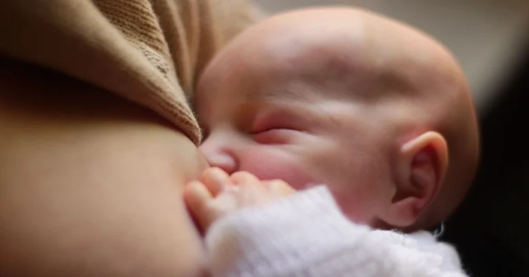The Dream Feed If you've ever tiptoed past your baby's nursery at 10 p.m., silently begging the universe to let them sleep past 2 a.m., you've probably already heard whispers about "dream feeding." It sounds almost too good to be true — sneak in a feeding while your baby is basically still asleep, and suddenly everyone gets a longer stretch of shut-eye. But like most parenting techniques that sound like magic, there's real strategy behind it, and getting it right makes all the difference between a dream feed that actually works and one that just leaves everyone more tired than before. Let's break down exactly what a dream feed is, when to start one, and how to execute it without turning your sleeping baby into a wide-awake, screaming baby. What Exactly Is a Dream Feed? A dream feed is a feeding you initiate on purpose, right before you head to bed, while your baby is still mostly asleep. You're not waiting for hunger cries. You're gently rousing your little one just enough to get a full feeding in, then tucking them right back into their crib. The easiest way to picture this is the "gas tank" analogy. Imagine your baby's stomach as a fuel tank that slowly empties overnight. If you top it off right before you turn in, there's a much smaller chance they'll run on empty and wake up hungry at 1 a.m. Hunger is one of the most common reasons babies stir in the middle of the night, so this one preemptive move can knock out a big variable. Here's the part that surprises a lot of parents, though: dream feeding usually doesn't add extra total sleep hours to your baby's night. What it actually does is shift the timing of their longest sleep stretch. Instead of your baby conking out at 8:30 p.m. and waking at 1:30 a.m., a well-timed dream feed nudges that same stretch to run from, say, 10:30 p.m. to 3:30 a.m. The total sleep length is similar — but now it overlaps with your sleep schedule instead of starting hours before you've even brushed your teeth. There's also a behavioral upside worth mentioning. When you feed your baby proactively, before hunger wakes them up screaming, you're not accidentally teaching them that crying is what summons food. Over time, this can support steadier daytime eating patterns too. Timing It Right: When and How Often Dream feeding isn't something to rush into during the newborn haze. Babies under four weeks old are still feeding every two to three hours around the clock — day and night — so their little systems simply aren't ready for a structured overnight strategy yet. Once your baby hits roughly the one-month mark, you've got a green light to experiment. The sweet spot for the actual feed tends to fall about two to three hours after your baby's bedtime feeding — think somewhere in the 9:00 to 10:30 p.m. range, though some parents push it as late as midnight, right before they themselves crash for the night. To set your baby up for a strong dream feed, it helps to load up on calories earlier in the evening. From around 4:00 p.m. onward, try offering more frequent feedings — sometimes called cluster feeding — every hour or two leading up to bedtime. Think of it as pre-filling that gas tank in stages rather than one giant top-off at the end. Some babies, even with a solid dream feed, still wake like clockwork around 3:30 a.m. If that's your situation, a second, quieter feed around 3:00 a.m. can bridge the gap. Once your baby seems ready to drop it, you can wean off gradually — trimming nursing time or bottle ounces every few days until it disappears naturally. The Actual Logistics: Doing It Without Fully Waking Your Baby This is a point that can easily confuse many parents. Dream feeding is a delicate dance, and there's a real technique to it. Set the mood first. Keep the room dark — a dim red night light is your friend here, since it's far less stimulating to a sleeping brain than white or blue light. Low, steady white noise should already be running, and you want to keep it going through the whole process. Watch for REM sleep before you move them. You're looking for those subtle signs — flickering eyelids, tiny squeaks, small twitches — that indicate your baby is in a lighter sleep phase. That's your window. Lift them gently, and always feed them cradled in your arms rather than in the crib itself; feeding a baby lying flat in their sleep space isn't safe. Trigger the reflex. Brush the bottle nipple or your breast lightly against your baby's cheek or lower lip. That contact usually kicks the natural rooting and sucking reflex into gear even while they're mostly dozing. If they're just not biting (literally), try stroking their cheek, murmuring softly, tickling a foot, or loosening the swaddle a bit to rouse them further. Don't mess with a good swaddle. If your baby is nursing or bottle-feeding just fine while still wrapped up snug, leave it alone. If you had to unswaddle to wake them enough to eat, re-wrap them near the end of the feed so the transition back to sleep feels seamless. Feed like it's a normal meal. Nurse for about five to ten minutes per side, or offer the same bottle volume they'd typically take during the day — often around three ounces. If fifteen or twenty minutes go by and they're clearly not interested, it's fine to call it there. Skip unnecessary diaper changes. A wet diaper on a peacefully sleeping baby is not worth the risk of jolting them fully awake. Save changes for dirty diapers, and handle those quietly, under dim light, either right before or midway through the feed. Burp if that's part of your baby's normal routine. For babies dealing with reflux, holding them upright anywhere from five to thirty minutes after the feed can make a real difference. A gentle pat while they're draped across your lap tends to keep them calm and drowsy rather than fully rousing them. Getting Them Back to Sleep If your baby stayed drowsy through the whole feed, the easiest move is simply laying them straight back down in the crib. Done. If they wake up more than you'd like during the process, lean on the classic 5 S's — swaddling, side or stomach positioning while you're holding them, shushing, gentle swinging motion, and offering a pacifier to suck on — paired with that ongoing white noise. One more trick worth knowing: the "wake-and-sleep" method. Right after you set your baby down, tickle their feet just enough that their eyes flutter open for a second. Then let them settle and drift off on their own. It sounds counterintuitive — waking them slightly to help them sleep better — but it can reinforce the skill of falling asleep independently rather than relying on being fed or rocked all the way down. Is It Actually Working? Give It a Fair Trial Don't judge a dream feed after one rough night. Commit to five to seven consecutive nights before deciding whether it's helping. Babies (and parents) need a little time to adjust to any new routine. Success looks like a shift in timing — that long sleep stretch moving later into the night so it lines up with your own bedtime. If your baby used to sleep hard from 8:30 p.m. to 1:30 a.m. and now sleeps from 10:30 p.m. to 3:30 a.m., that's two extra hours of sleep you get to keep for yourself. That's the win. On the flip side, it might be time to drop the dream feed if: Your baby already goes to bed relatively late (9:00–10:00 p.m.), meaning their natural long stretch already overlaps with yours. The feed seems to yank them out of deep sleep and leaves them cranky or wide awake instead of drowsy. They just won't rouse enough to actually eat a full feeding. They keep waking at the same time regardless — say, 1:30 a.m. or 4:00 a.m. — no matter what you do at 10 p.m. If you recognize any of these signs, a dream feed may not be providing much benefit for your baby, and that is completely okay. Not every strategy fits every kid. Knowing When (and How) to Stop Many families gradually stop using the dream feed between 4 and 9 months, often a few weeks after their baby begins consistently sleeping from the dream feed through the morning. There is no need to stop it all at once. Gradually shorten nursing sessions or reduce bottle volume, or swap the feed out for a pacifier if your baby just wants that comfort rather than actual nourishment. One last practical note: once teeth start coming in, it's smart to shift feedings back into waking hours and get into a habit of brushing before bed. Milk sitting on baby teeth overnight isn't great for enamel, so this is a good natural cue that dream feeding's days are numbered anyway. The Bottom Line Dream feeding isn't a guaranteed fix for every family, but for many parents, it's a genuinely useful tool — one that can buy back a couple of precious hours of uninterrupted sleep during an exhausting stage of life. The key is patience: give it a real trial run, pay attention to how your specific baby responds, and don't be afraid to adjust or drop it entirely if it's not pulling its weight. Every baby's sleep is a little different, and the "right" approach is always the one that actually works for the family living it.