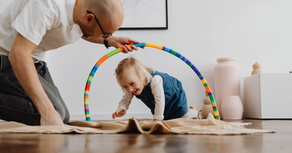 30 Easy Indoor Activities for Toddlers That They’ll Love 3 Toddler crawling through a homemade indoor obstacle course in a cozy family living room