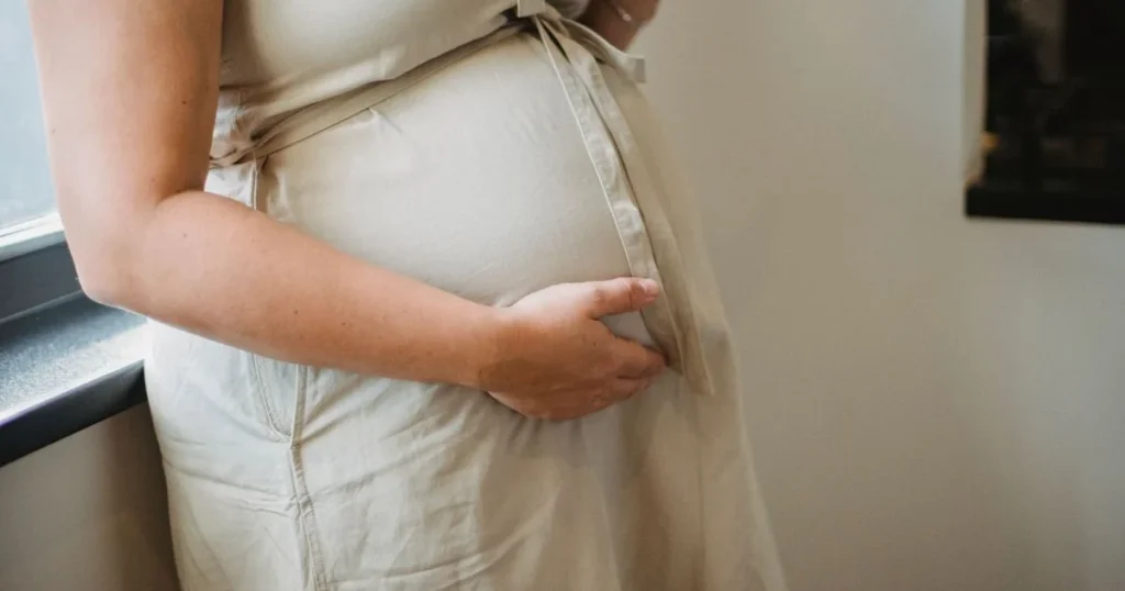 Pregnant woman resting her hands on her belly 